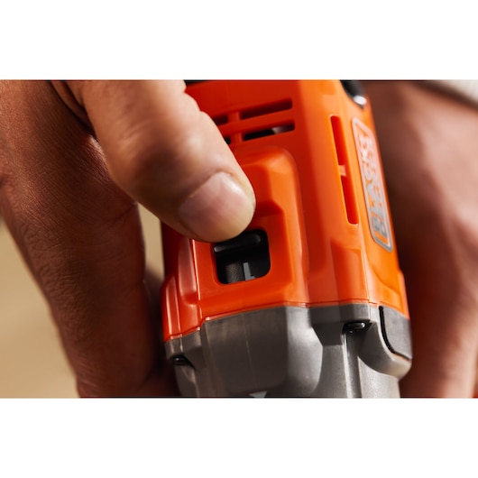 Close-up of hand operating BLACK+DECKER BCD382D1 orange power tool control switch.