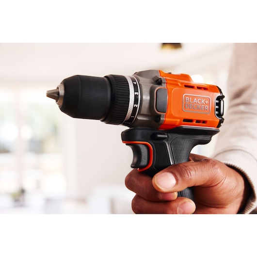 Photo of BLACK+DECKER cordless drill BCD382D1, black and orange, held in hand, close-up view.