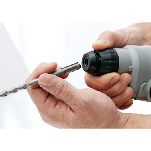 Close-up photography of hands inserting drill bit into BLACKDECKER BCD900E2K power tool.
