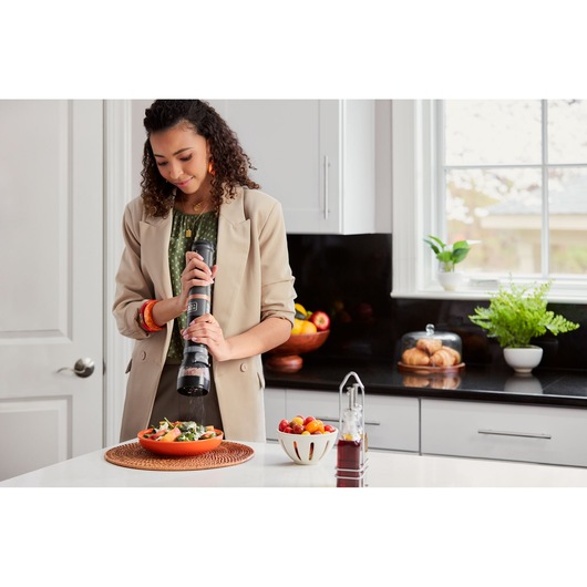 BLACKDECKER BCKM1011KGF cordless kitchen mixer used by a person preparing salad in a modern kitchen.
