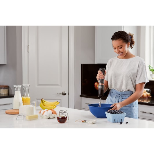 BLACKDECKER BCKM1011KGF hand mixer in use with a bowl of blueberries in a modern kitchen.
