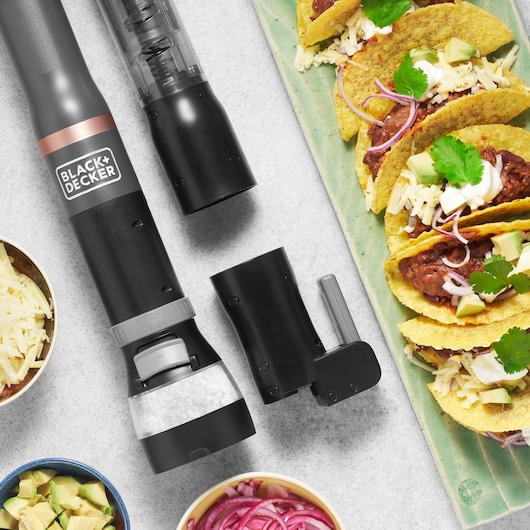BLACK+DECKER BCKM1016KSG electric seasoning grinder with attachments on kitchen counter near tacos and food bowls, top view.