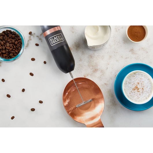 BLACK+DECKER BCKM1011KGF handheld milk frother with black handle on white surface, coffee beans and cup nearby.