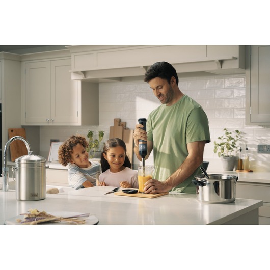 BLACKDECKER BCKM1011KGF hand blender mixing orange liquid in a kitchen scene with people.
