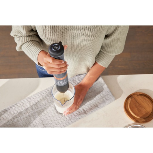 Photo of BLACKDECKER hand blender BCKM1016KSG mixing ingredients in a measuring cup on a kitchen counter.