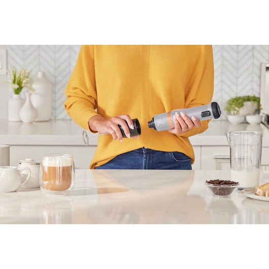 BLACKDECKER BCKM1016KSG handheld milk frother used in kitchen near coffee cup and beans.