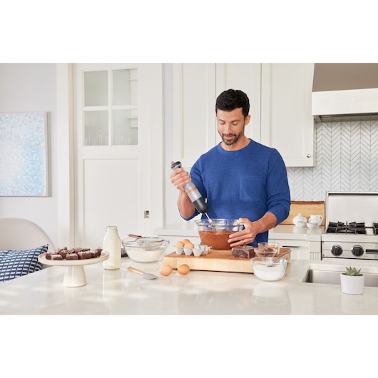 BLACKDECKER BCKM1016KSG hand mixer used in a kitchen with baking ingredients and brownies on the counter.