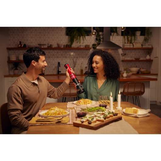 BLACKDECKER BCKM101SPFF electric pepper mill used at a dining table with pasta dishes and candles.
