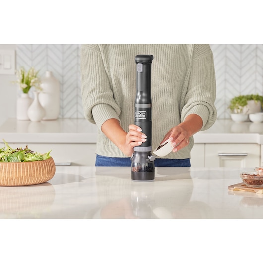Photo of BLACK+DECKER electric pepper grinder BCKM101SPFF being filled with peppercorns in a modern kitchen.