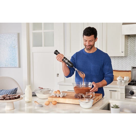 BLACKDECKER BCKM101WHFF hand mixer used in kitchen for mixing ingredients in glass bowl.