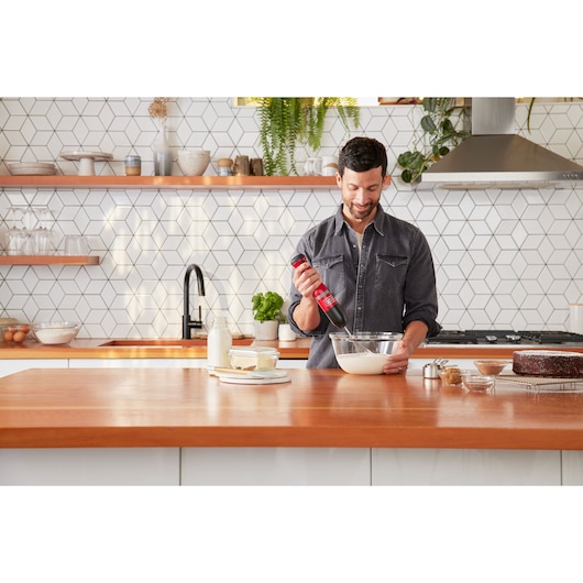 Photo of BLACKDECKER BCKM101WHFF hand mixer in use mixing batter in a modern kitchen.