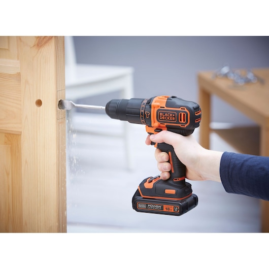 BLACKDECKER BCKSB05 cordless drill being used to drill a hole in a wooden door indoors.