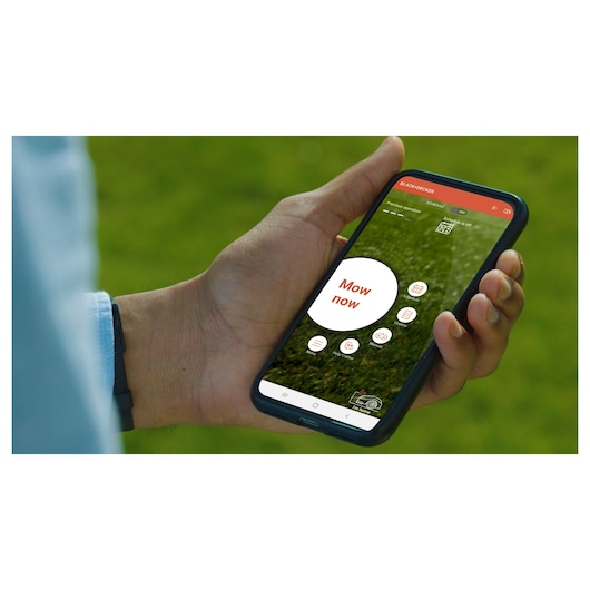 Photo of hand holding smartphone showing BLACK+DECKER BCRMW121 app interface for robotic lawn mower control.