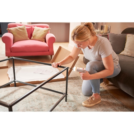BLACKDECKER BCRTA01 cordless screwdriver used to assemble metal table frame in living room.