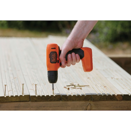 BLACKDECKER BDCD8 cordless drill used for screwing wooden planks outdoors.
