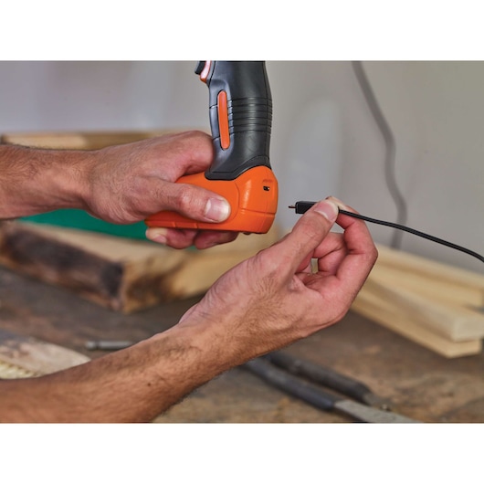 Photo of hands plugging a charging cable into a BLACKDECKER cordless drill BDCD8.