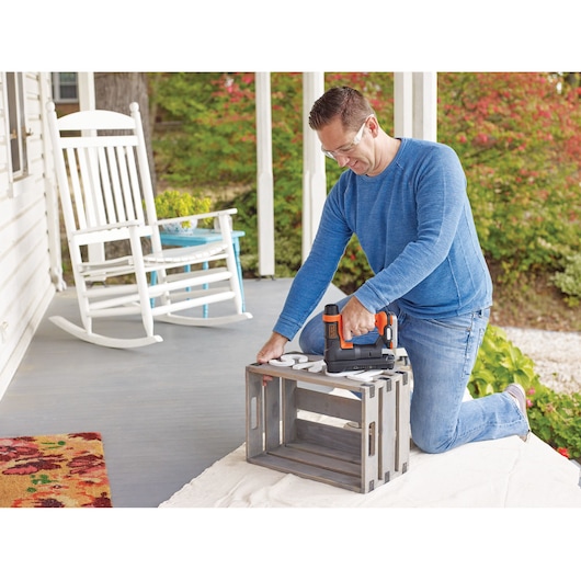 BLACKDECKER BDCT12N cordless sander in use on a wooden crate outdoors, product photography.