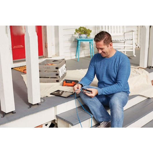 Photo of BLACKDECKER BDCT12N multi-tool on porch, near a person in blue shirt using wire stripper, with tools visible.