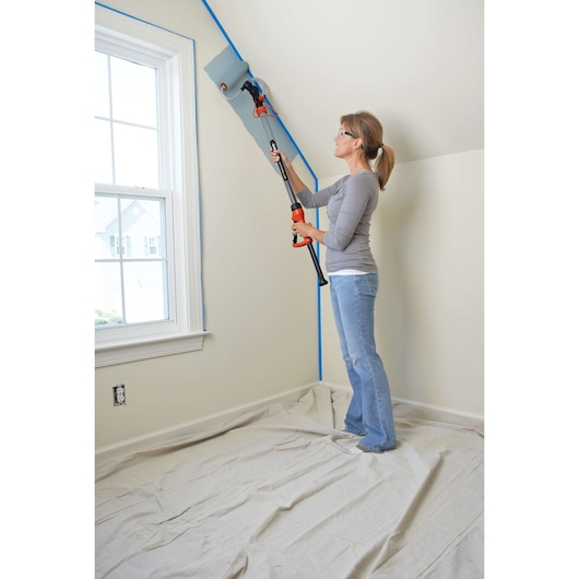 Photo of BLACK+DECKER BDPR400 paint roller with extension pole used to paint a wall near a window.