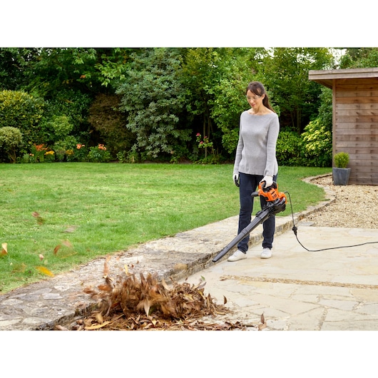 BLACKDECKER BEBLV301 leaf blower in use outdoors, blowing leaves from patio, corded, photography.