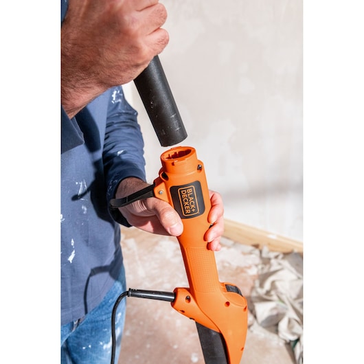 Person attaching tube to BLACK+DECKER BEDW700 orange tool in a room under renovation.