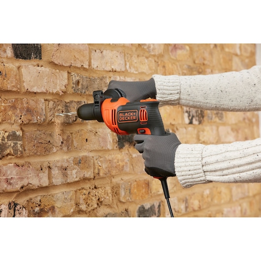 Photo of BLACK+DECKER BEH550 hammer drill in use, drilling into a brick wall.
