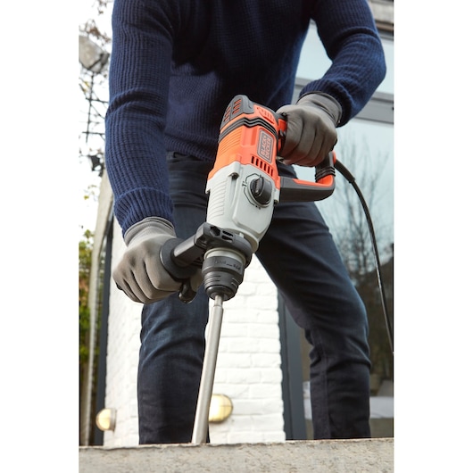 BLACKDECKER BEHS02K rotary hammer drill in use, orange and grey design, held by person wearing gloves.