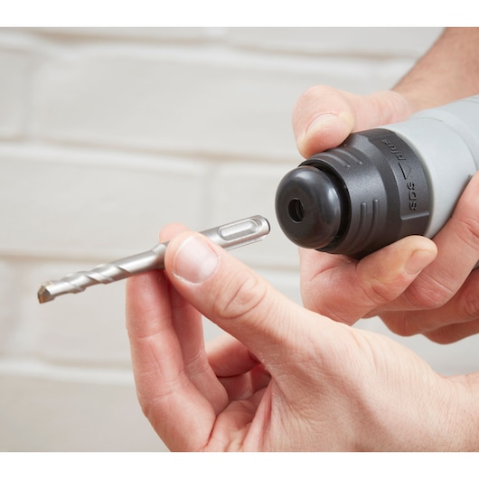 BLACKDECKER BEHS02K rotary hammer close-up showing hands changing SDS drill bit.