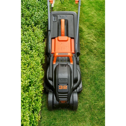 Photo of BLACKDECKER BEMW351 lawn mower on grass, top view showing black and orange body and wheels.