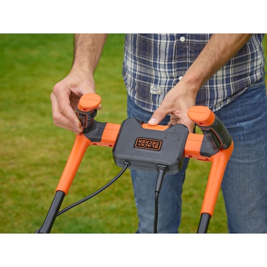 Photo of BLACKDECKER BEMW481BGL2 lawn mower handle with orange and black controls on grass.