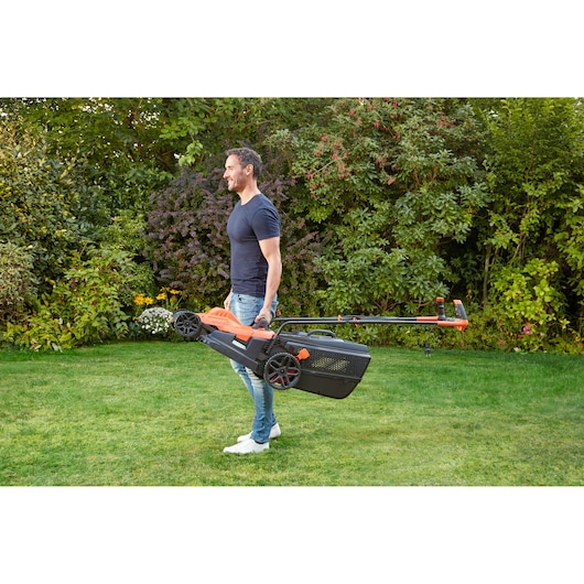 BLACKDECKER BEMW481BGL2 lawn mower with orange and black color, carried by person outdoors on grass.
