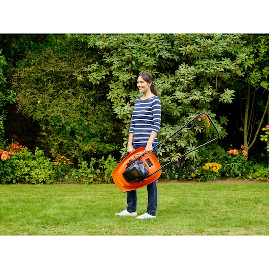 BLACK+DECKER BEMWH551 orange hover lawn mower held upright by person in garden.