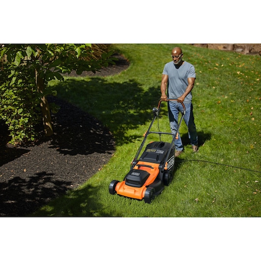 BLACK+DECKER BEMWP400-QS electric lawn mower in use on a grassy lawn, black and orange design.