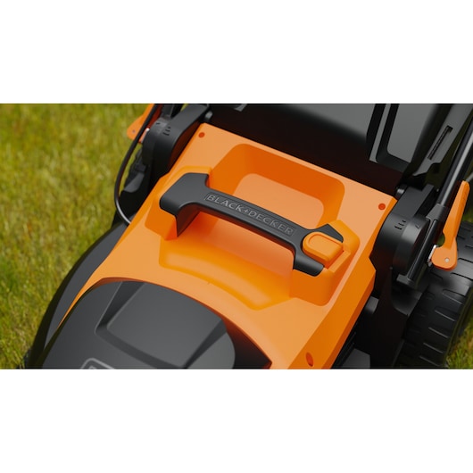 Close-up photo of BLACK+DECKER BEMWP400-QS lawn mower handle and orange control panel on grass.
