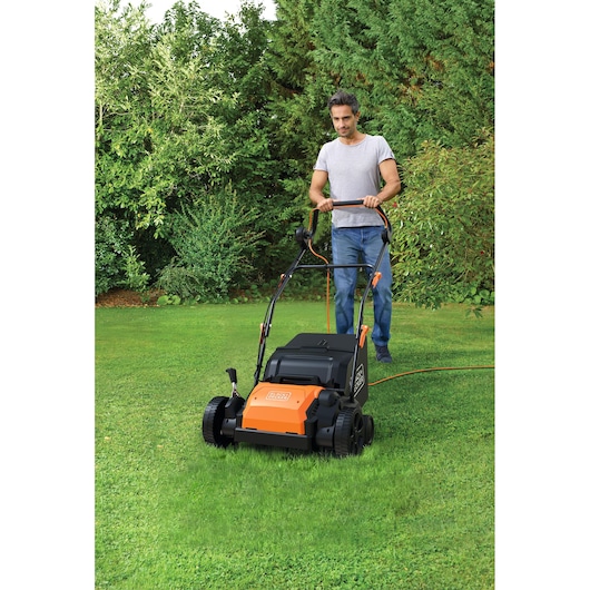 BLACKDECKER BEOEP320-QS lawn scarifier with orange and black design in use on green grass.