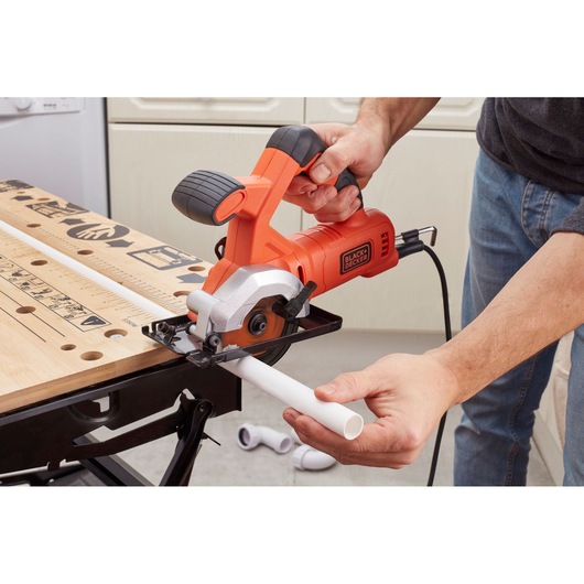 Photo of BLACK+DECKER BES510 compact circular saw cutting a white plastic pipe on a workbench.