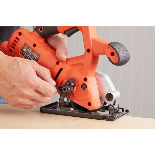 Photo of BLACK+DECKER BES510 compact circular saw being adjusted on a wooden surface, close-up view.