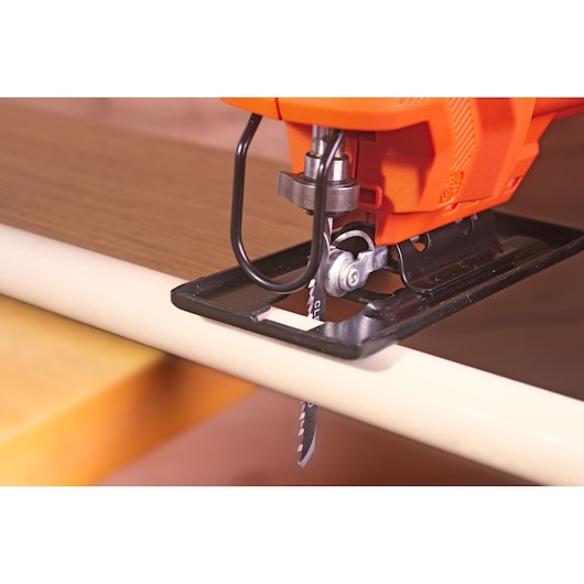 BLACKDECKER BES603 jigsaw cutting wood, close-up view showing blade and base plate.