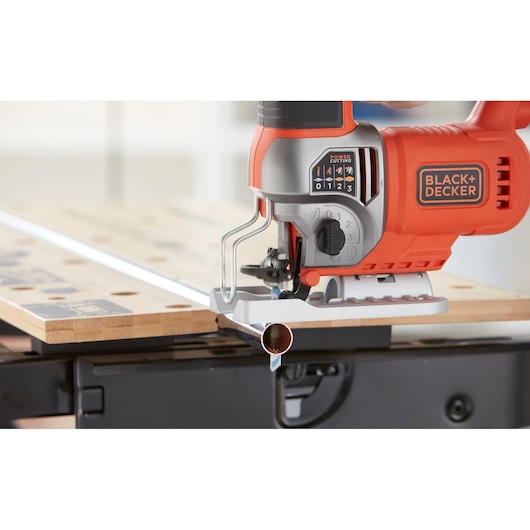 Photo of BLACK+DECKER BES610K jigsaw cutting a metal pipe on a workbench, close-up angle.
