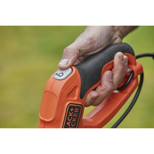 Photo of BLACKDECKER BESTE625 power tool handle with thumb pressing power button, close view.