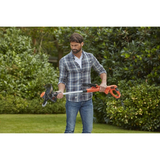 BLACKDECKER BESTE628 grass trimmer with orange handle and silver shaft held outdoors.