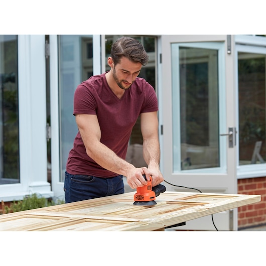 BLACKDECKER BEW200 sander used on wooden door outdoors.