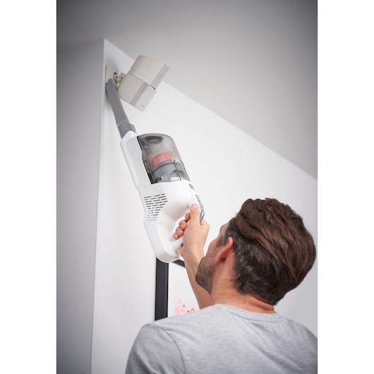 BLACKDECKER BHFEA515J vacuum cleaner used for cleaning a high corner, photography shows handheld operation.