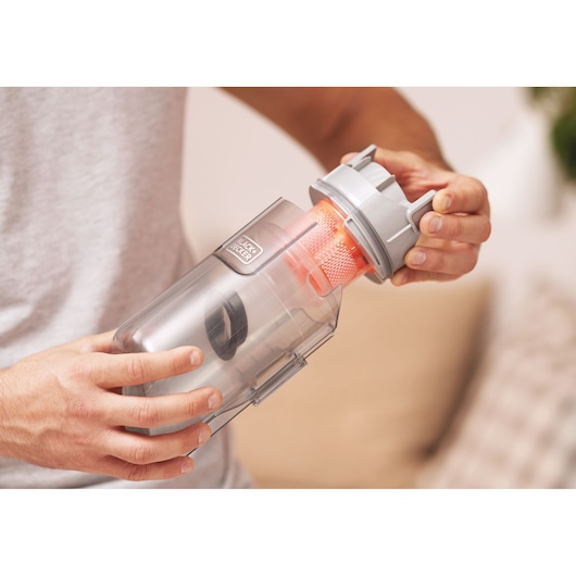 BLACK+DECKER BHFEA515J vacuum cleaner dustbin being emptied by hand, close-up view.