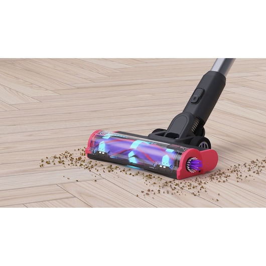 BLACK+DECKER BHFEA640WP vacuum cleaner head in action on light wood floor with scattered debris, front angle.