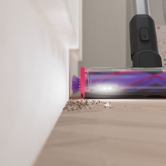 BLACKDECKER BHFEA640WP cordless vacuum cleaner head with LED lights cleaning debris along wall, side view.