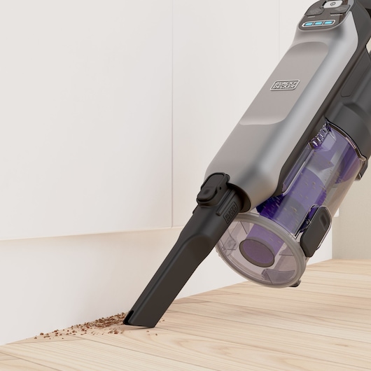 BLACKDECKER BHFEA640WP cordless vacuum cleaning debris along a baseboard, close-up side angle.
