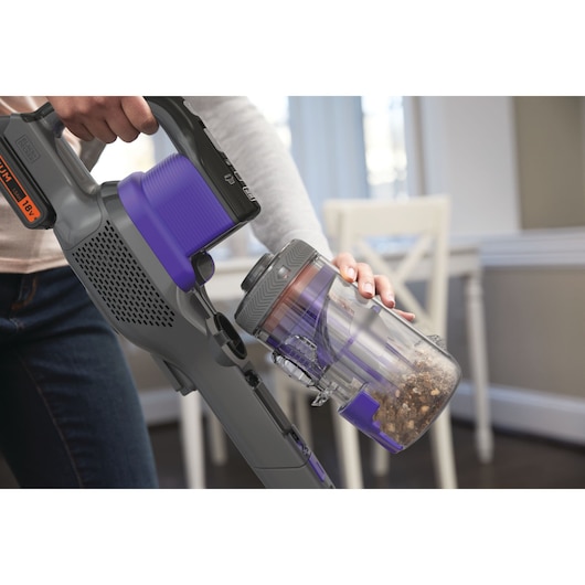 BLACKDECKER BHFEV182CP cordless vacuum in use, showing dust container being emptied indoors.