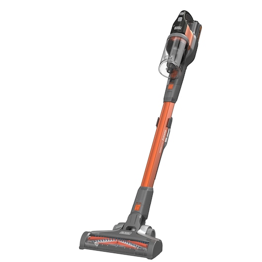 A BLACK+DECKER cordless stick vacuum cleaner with an orange and grey design, featuring a transparent dust container and motorized brush head.