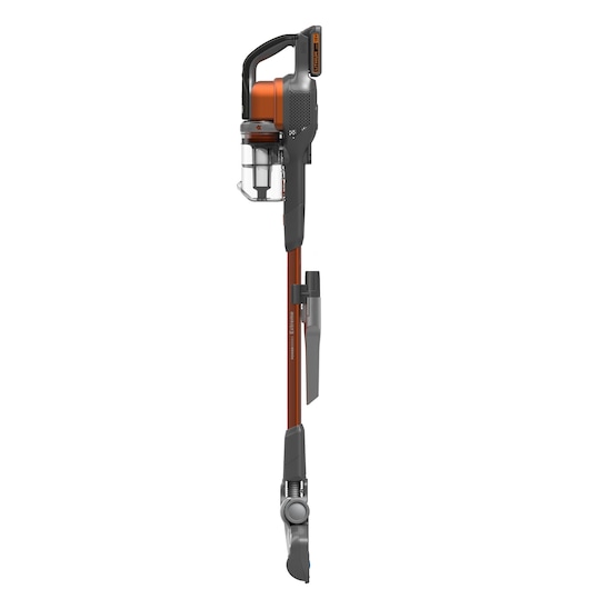 A cordless stick vacuum cleaner with orange and black accents, featuring a transparent dust container and an attached nozzle accessory, shown in a vertical position against a white background.